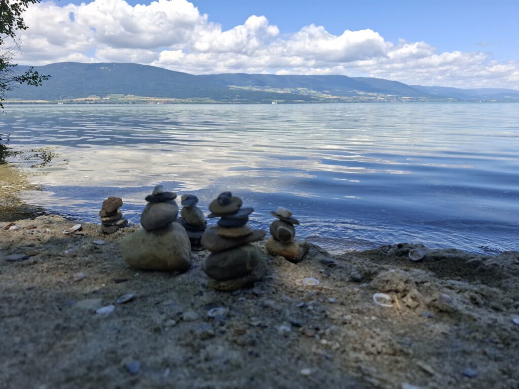 Cairns de galets au bord du lac de Neuchâtel, face au Jura